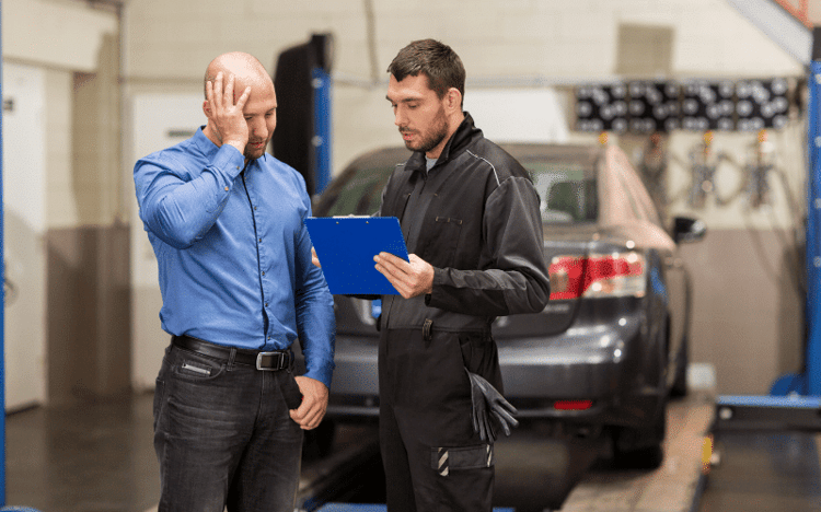 Auto repair shop mechanic showing frustrated owner a clipboard detailing an insurance short pay