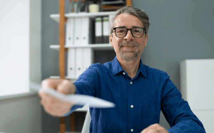 Happy Minneapolis business owner handing you a paycheck from his payroll service