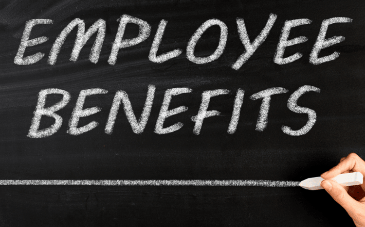 Small business owner hand writing employee benefits on a chalkboard